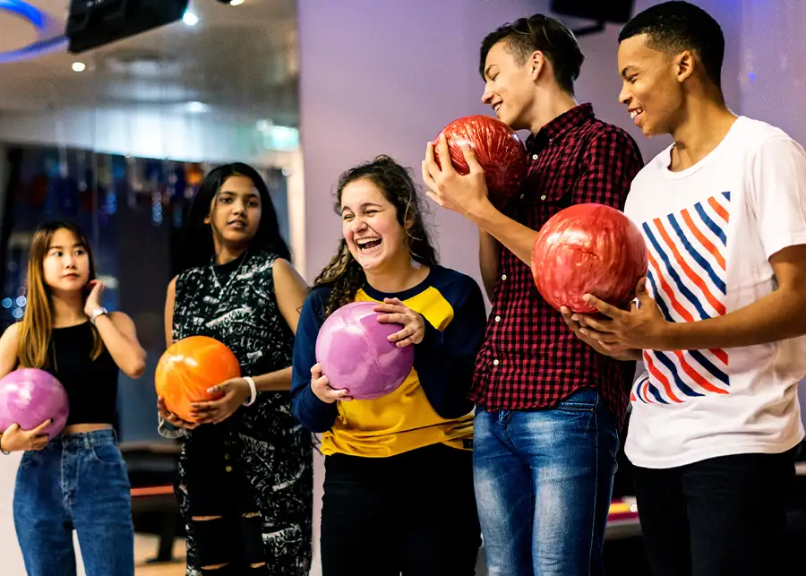 Group of teenagers holding bowling balls and laughing together at Championship Lanes in Anderson, IN - Ultimate Unlimited Party